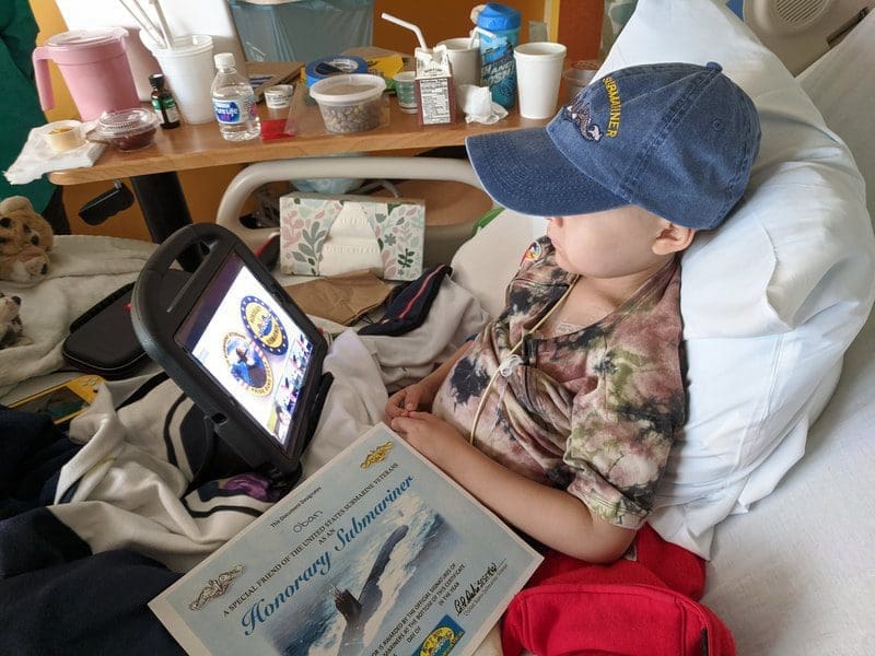Child in hospital bed watching tablet.