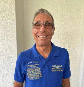 Man smiling in blue polo shirt indoors.